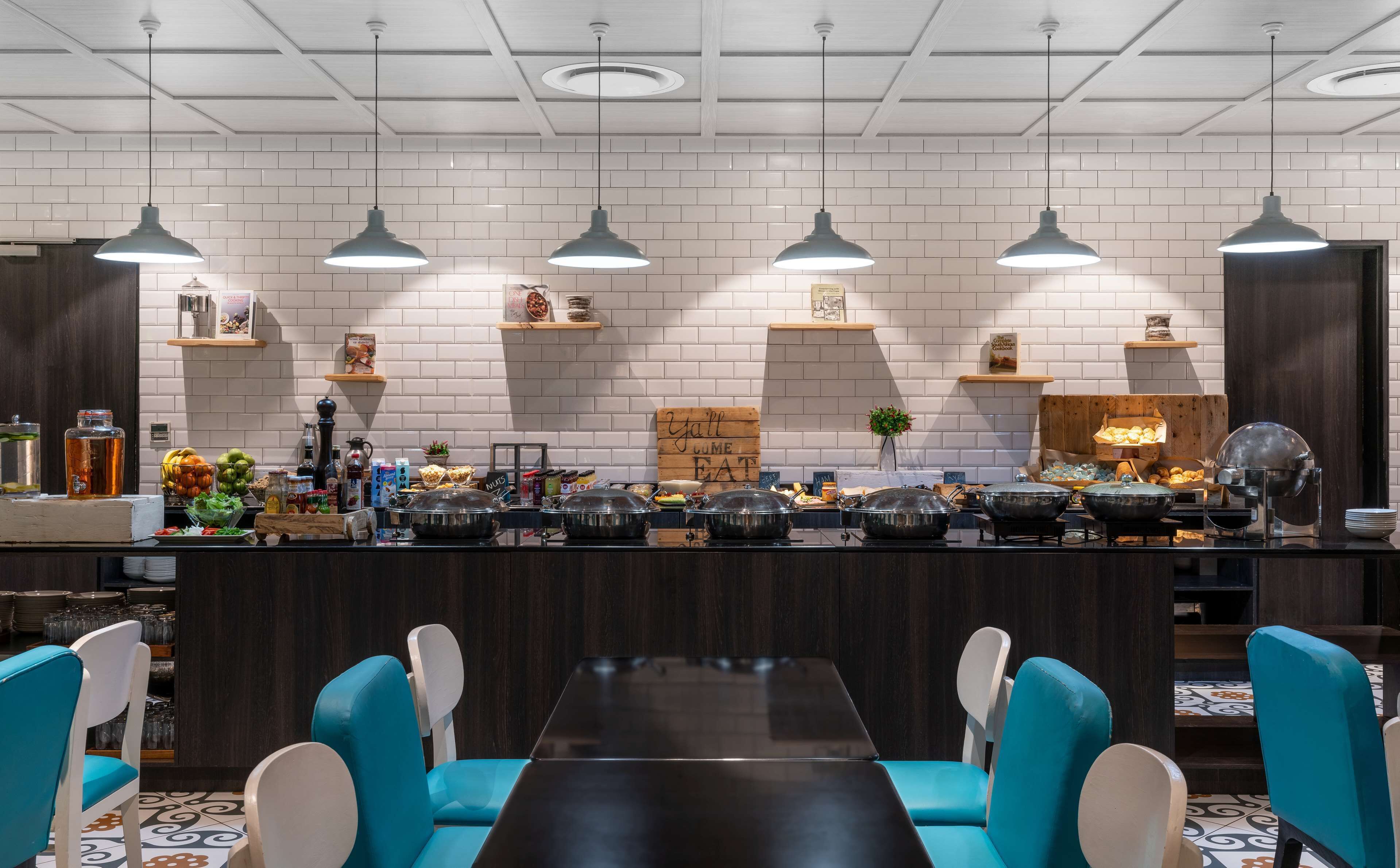 Une cuisine moderne avec des murs en briques blanches, des luminaires suspendus et un îlot central où sont disposés des aliments et une pancarte sur laquelle on peut lire : « Vous allez adorer nos LIME EAT ».
