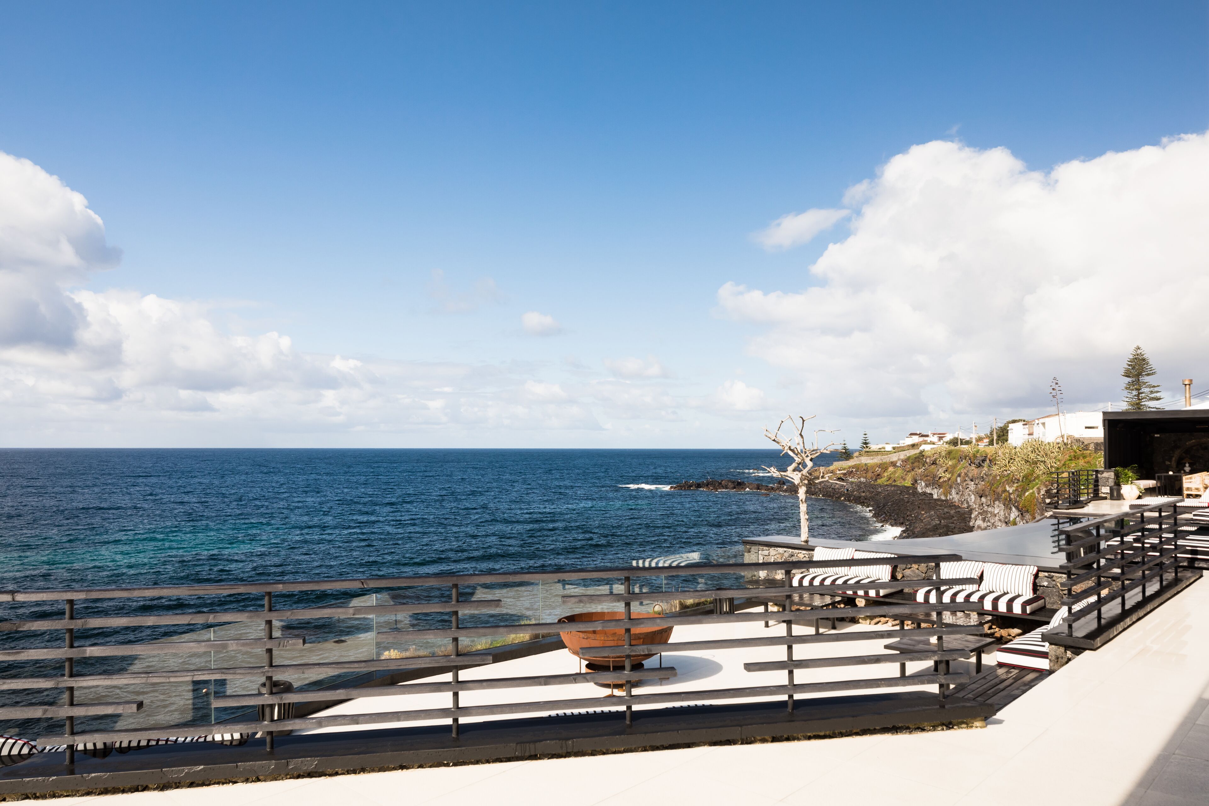A seaside terrace with outdoor seating and a view of the ocean.