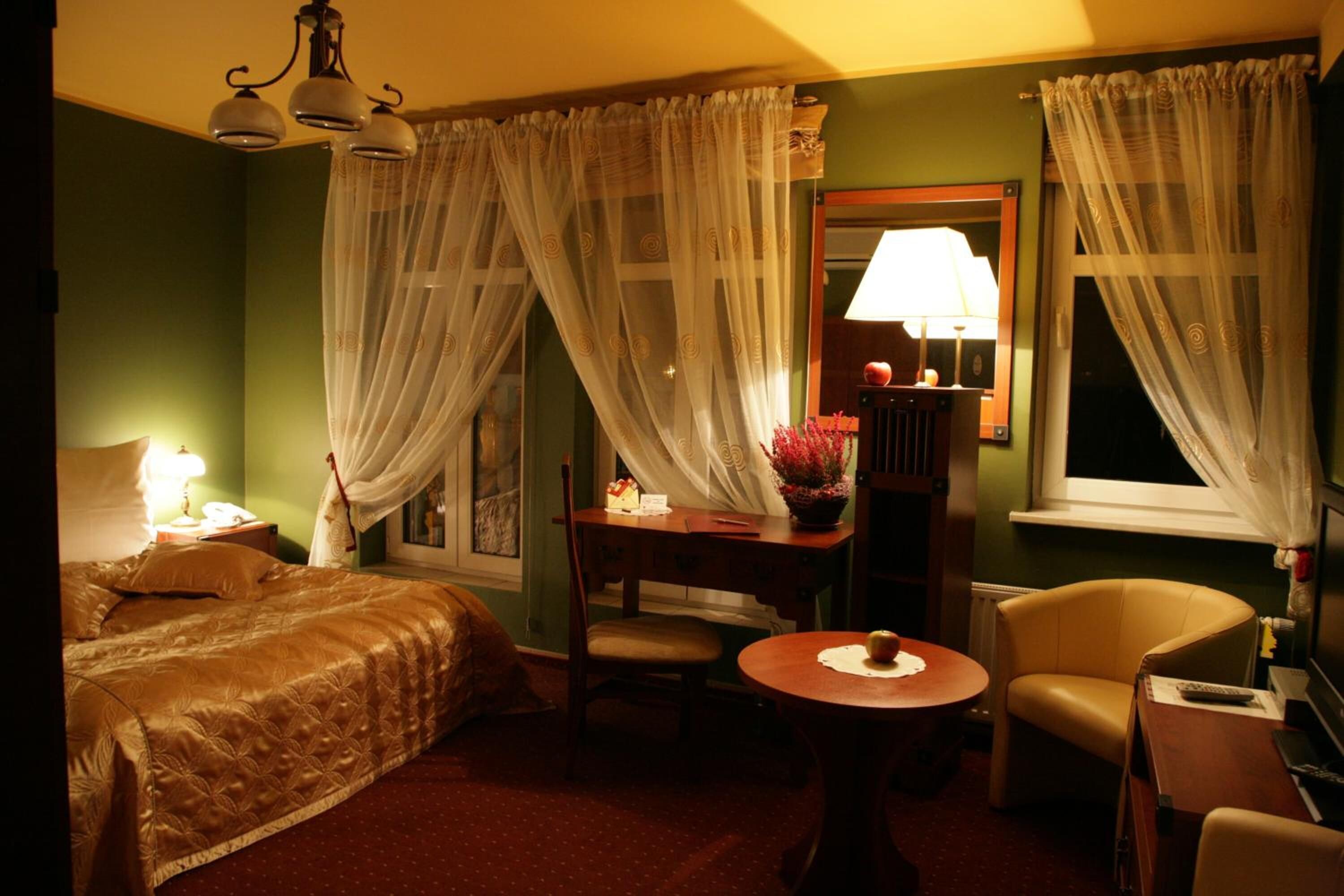 Ein Hotelzimmer mit einem Bett, einem Schreibtisch mit Lampe, einem Sessel und einem kleinen Tisch.