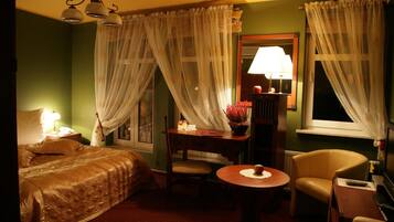 Ein Hotelzimmer mit einem Bett, einem Schreibtisch mit Lampe, einem Sessel und einem kleinen Tisch.