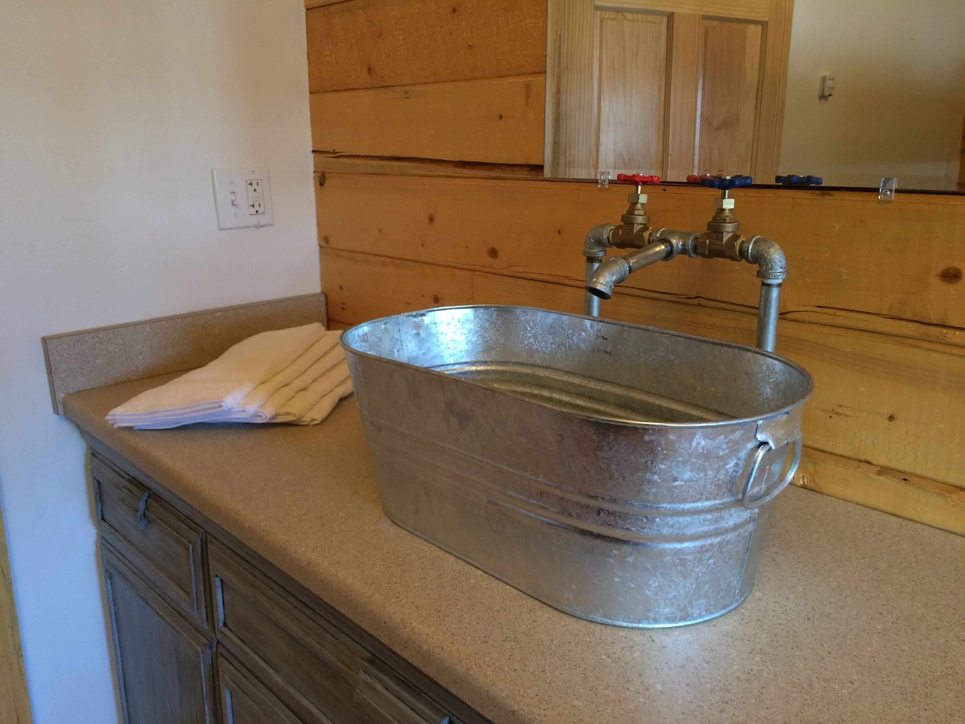 A metal basin sink with a faucet on a beige countertop.
