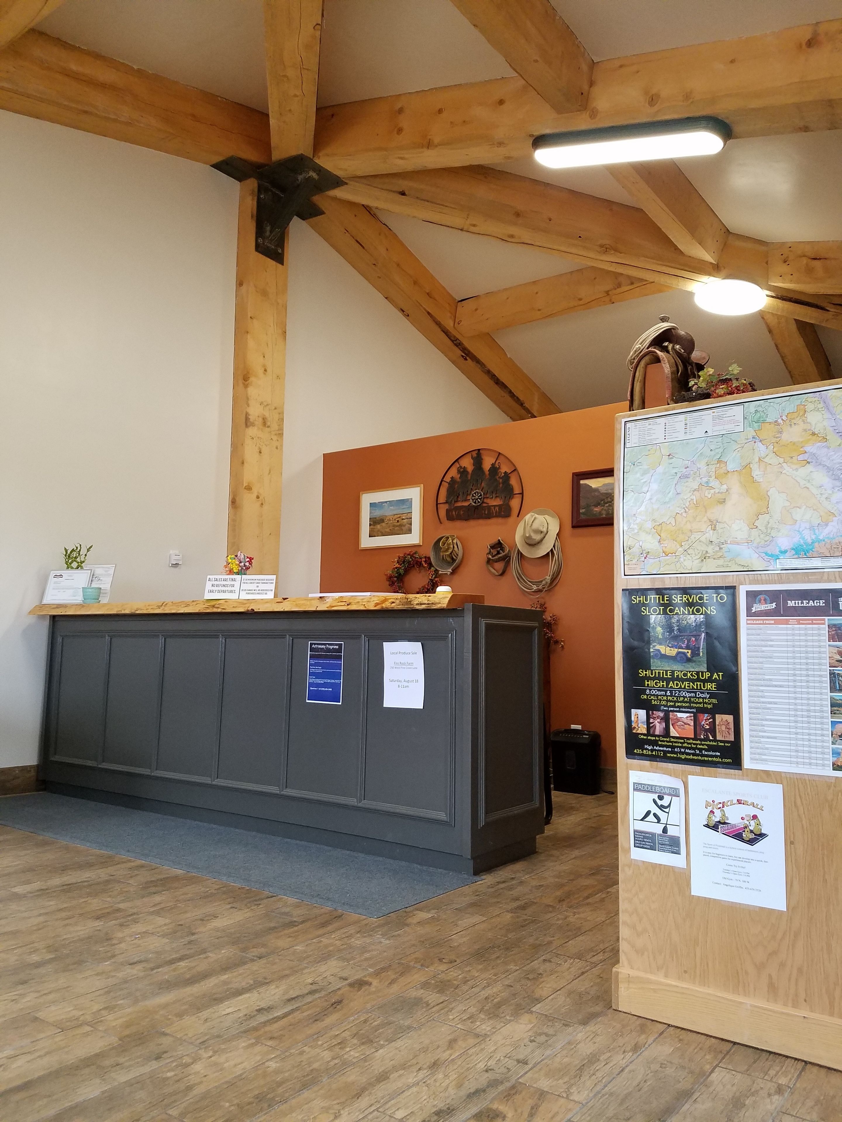 Un comptoir d’accueil avec un plan de travail en bois, une carte et divers affiches d’information.