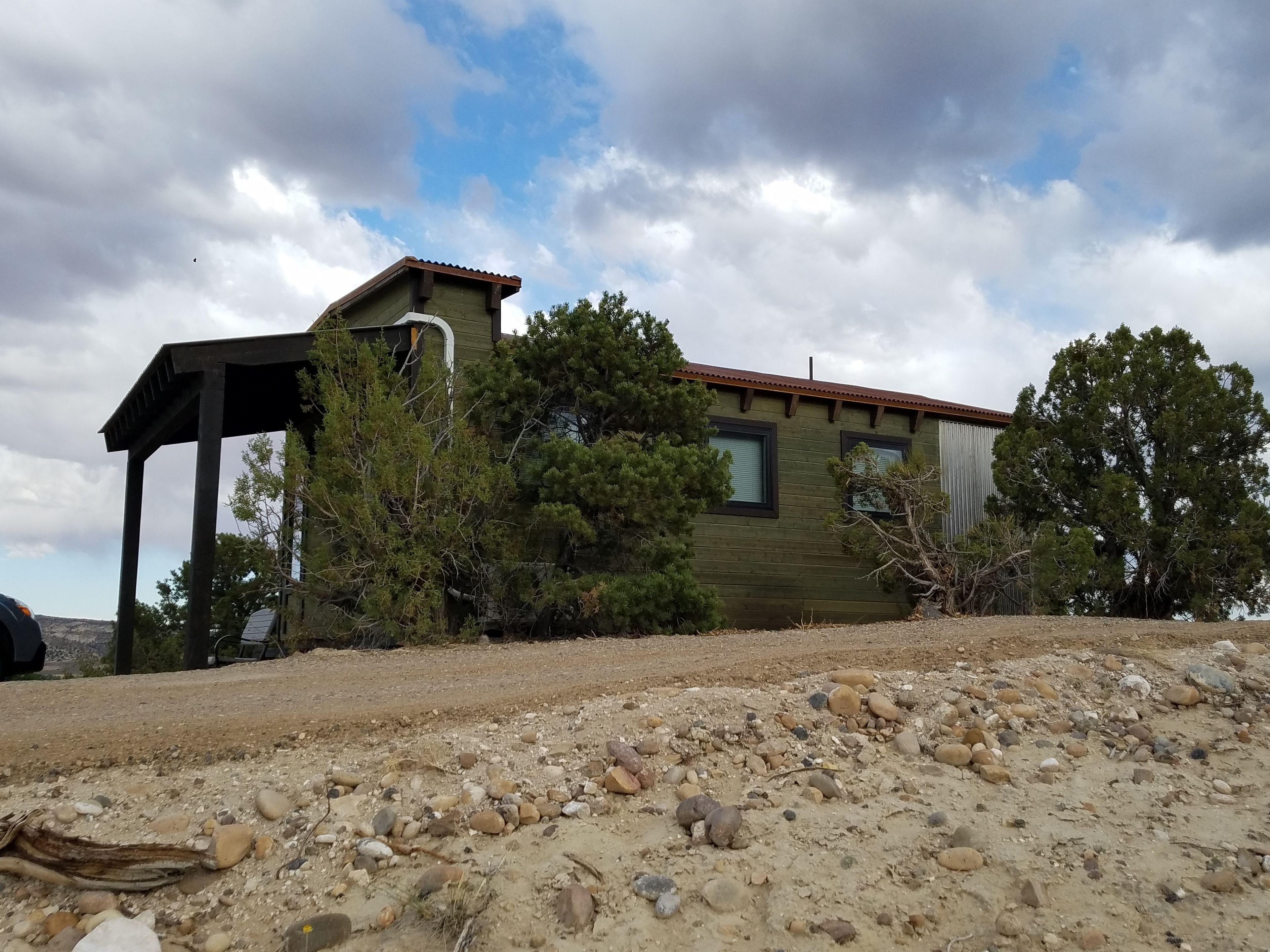 A rustic cabin with a wooden exterior, a covered porch, and a view of a rocky landscape.