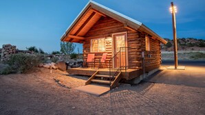 A log cabin with a porch, steps, and two chairs. - Escalante Grand Resort (Escalante)