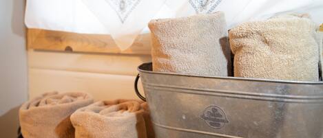 A metal container with folded towels and a patterned white cloth.