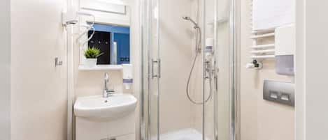 Un baño moderno con ducha de vidrio, lavamanos y espejo.