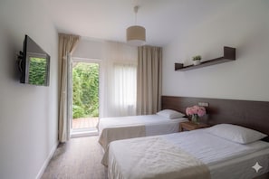 A hotel room with two beds, a TV, a small shelf with a plant, and a window with curtains. - Smart2Stay Magnolia (Warsaw)