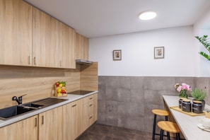 Una cocina con armarios de madera, un fregadero, una encimera y una pequeña barra con taburetes y tarros etiquetados 'TEA' y 'SUGAR'.