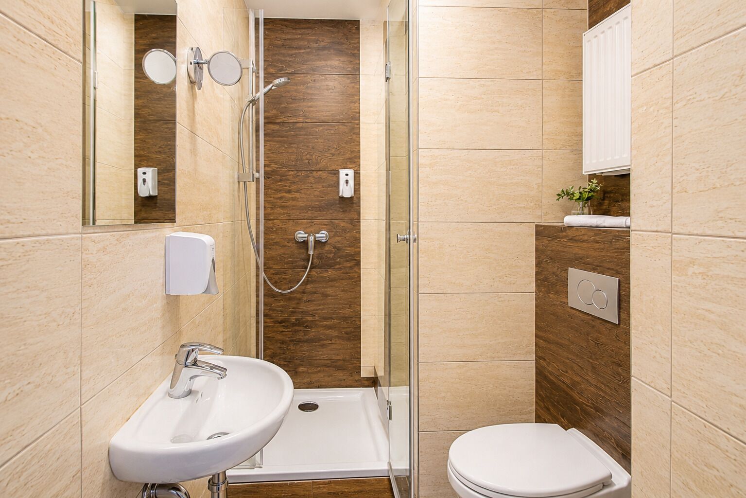 Uma casa de banho moderna com chuveiro, sanita e lavatório.