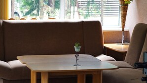 A modern living room with a sofa, a small wooden table with a flower vase, and a lamp. - Holiday Home Zgorzale by Lake Radunskie (Zgorzałe)