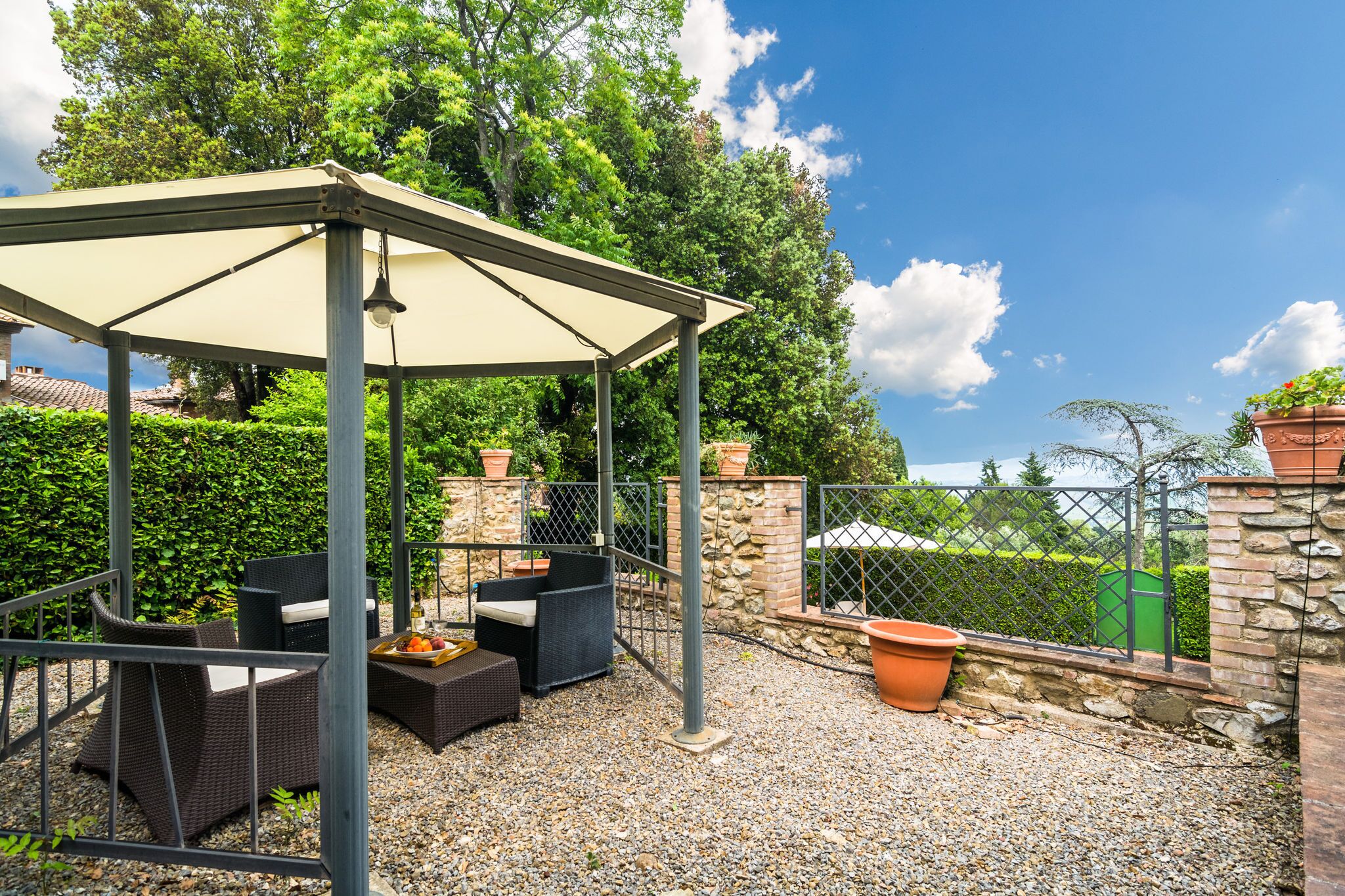 Un espace extérieur aménagé avec des meubles en osier et une pergola, le tout abrité.