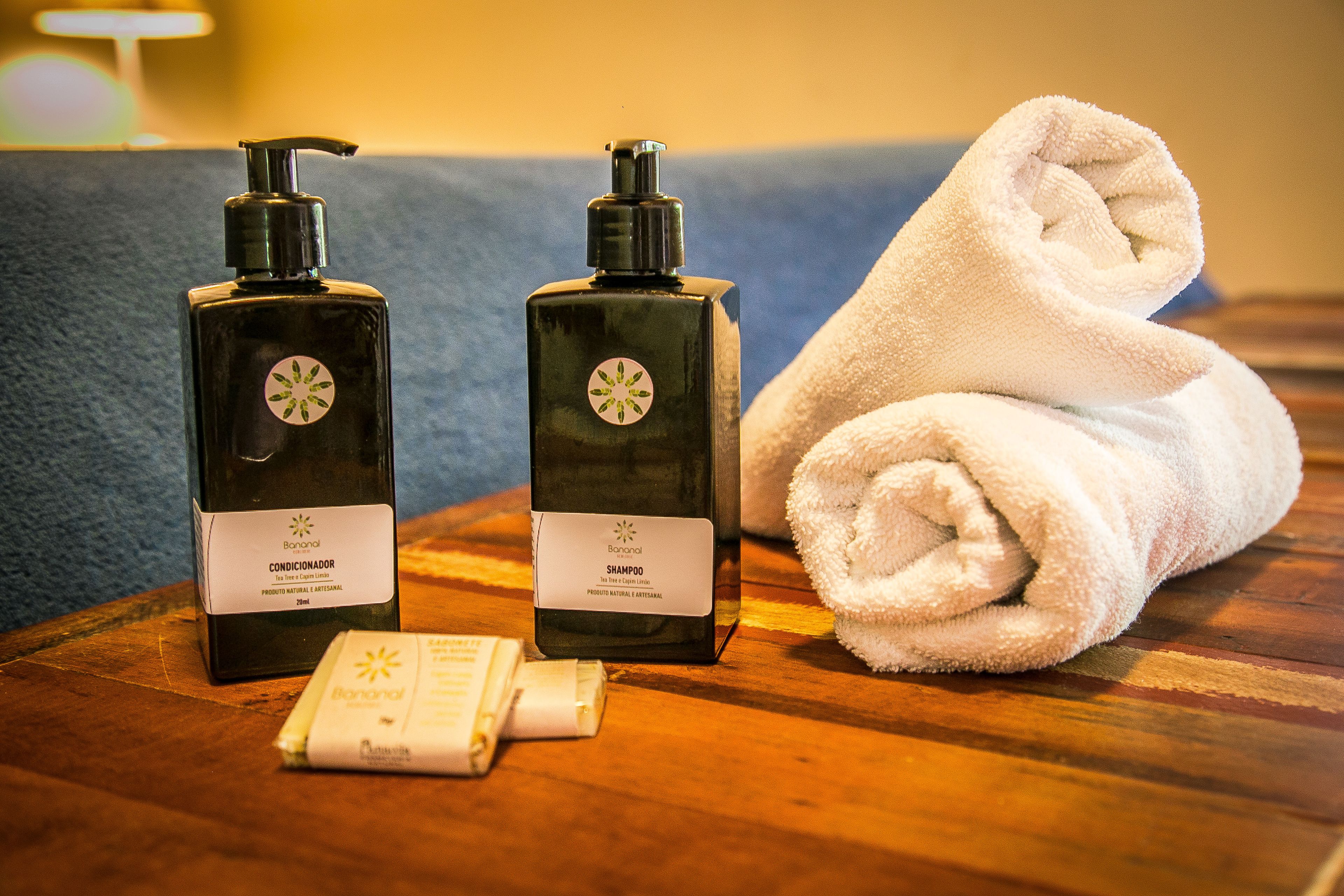 Two bottles of Bonanal conditioner and shampoo, a white towel, and a small bottle of lotion on a wooden surface.