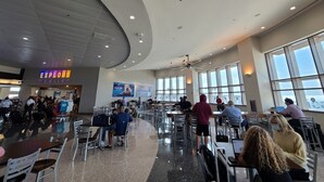 A spacious cafeteria with high ceilings, large windows, and a curved ceiling design.