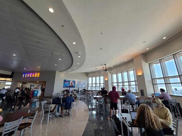 A spacious cafeteria with high ceilings, large windows, and a curved ceiling design. - Texas Inn and Suites City Center at University Dr. (Edinburg)