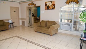 A spacious lobby with a large window, a ceiling fan, and a patterned rug.