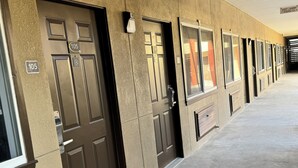 A row of hotel rooms with beige walls and dark brown doors, each marked with a number.