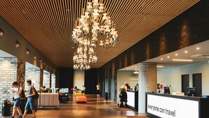 Een moderne lobby met een centrale kroonluchter, een receptiebalie en zithoeken.