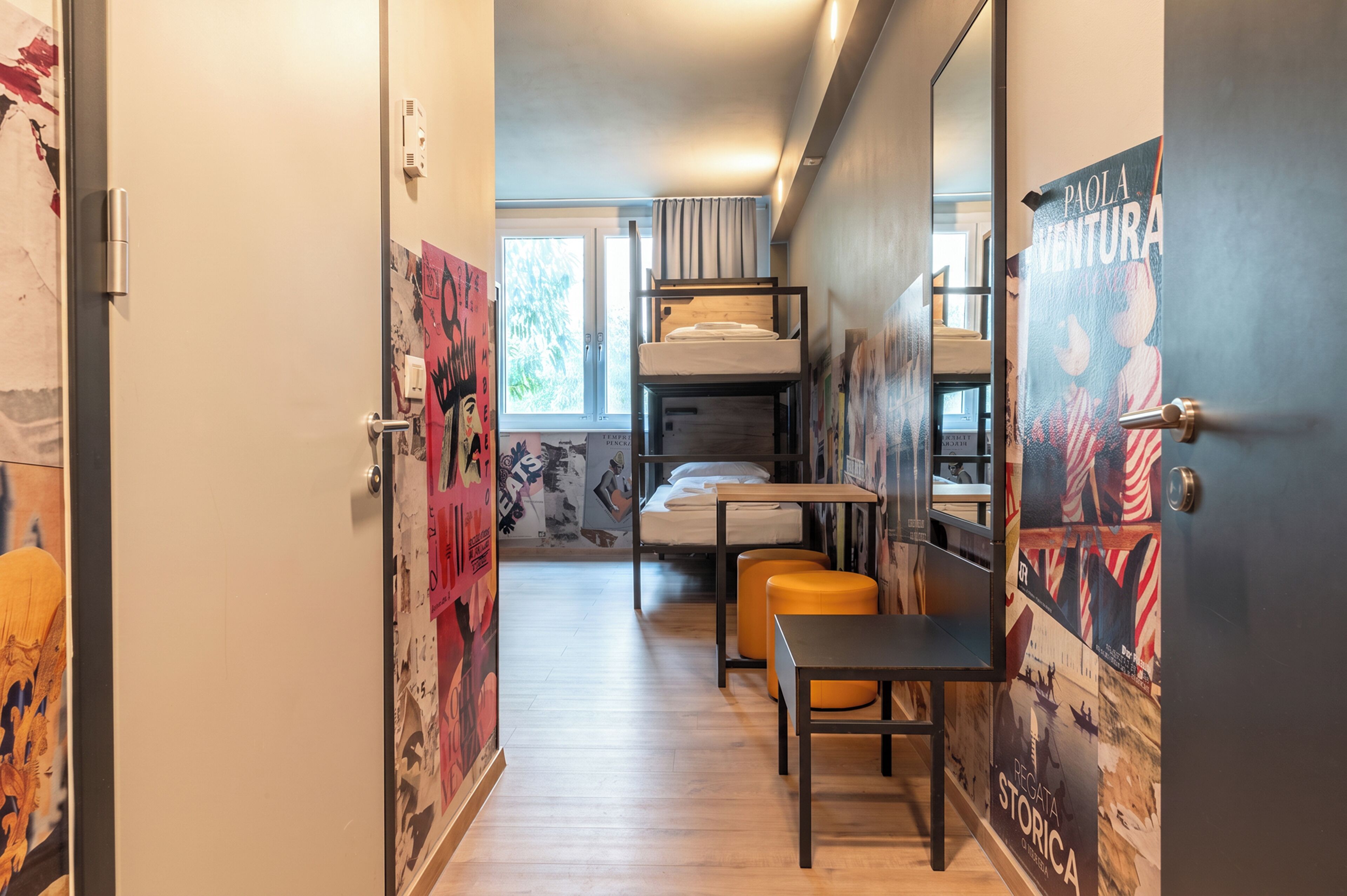 A dormitory room with bunk beds, a desk, and a chair.
