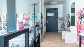 A hallway with bunk beds, a door, and walls adorned with various posters and artworks.
