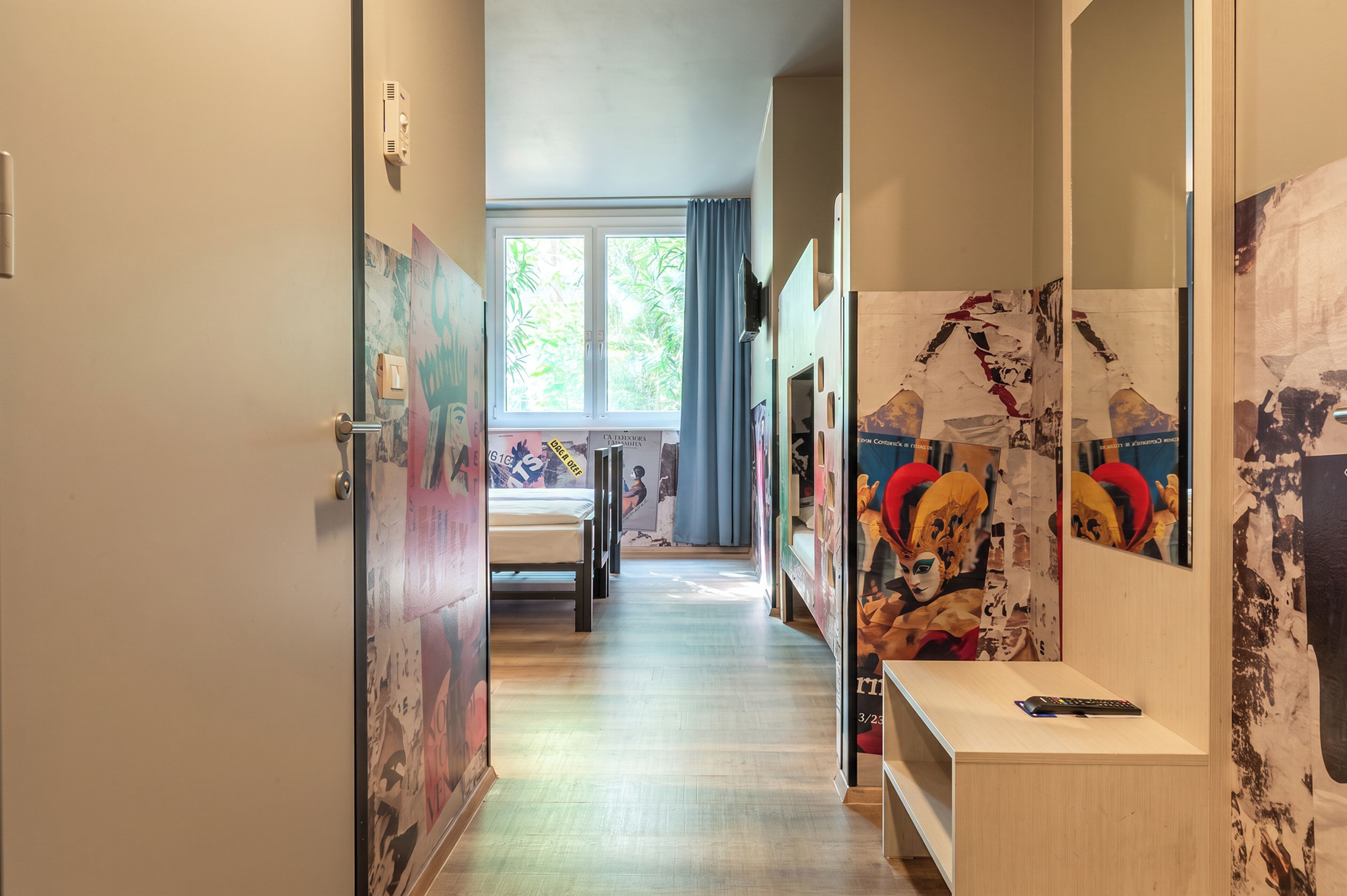 A hallway with a bed, a desk, and a mirror.