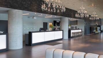 Un'ampia hall con una moderna reception, area salotto e lampadari decorativi.