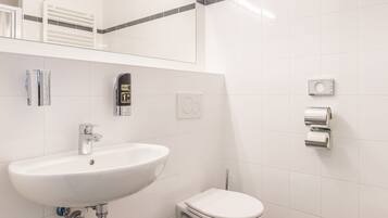 A modern bathroom with a white sink, toilet, and towel rack.