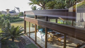 Una casa moderna con un balcón de vidrio que da a un jardín.