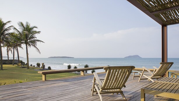 Una terraza de madera con sillones de descanso con vistas al océano.