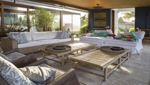 Un patio amplio con dos sofás blancos, mobiliario de mimbre y un ventilador de techo.