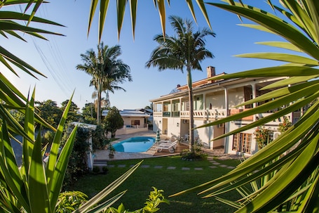 Una piscina al aire libre, sombrillas, sillones reclinables de piscina