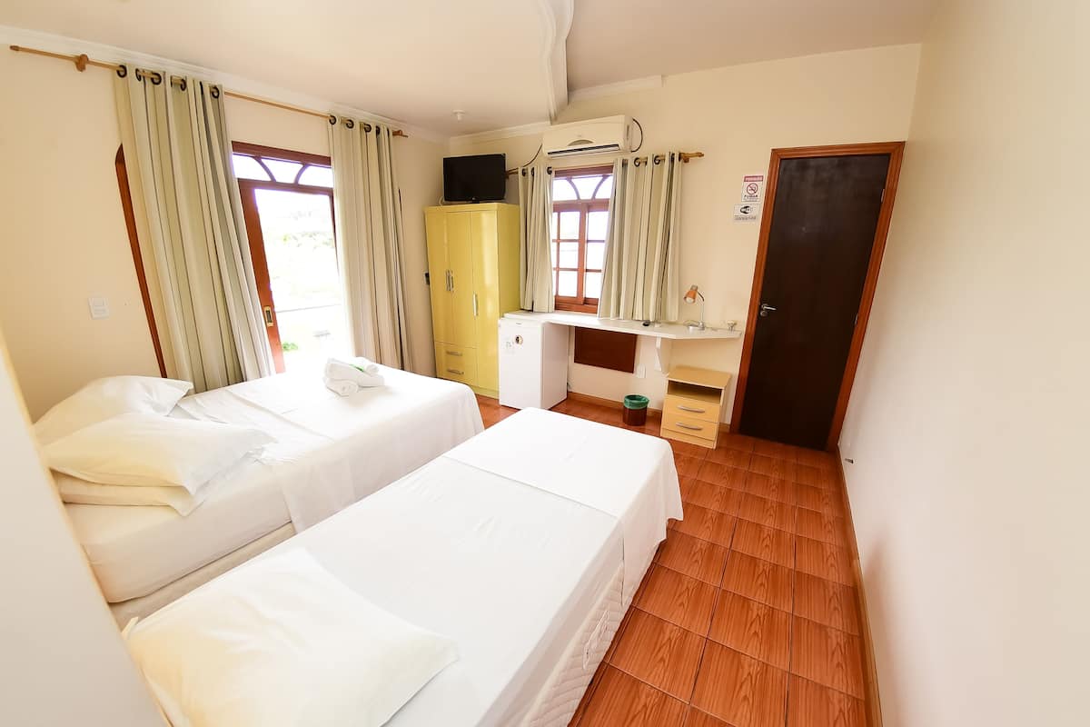 A hotel room with two beds, a wardrobe, a desk, and a door.