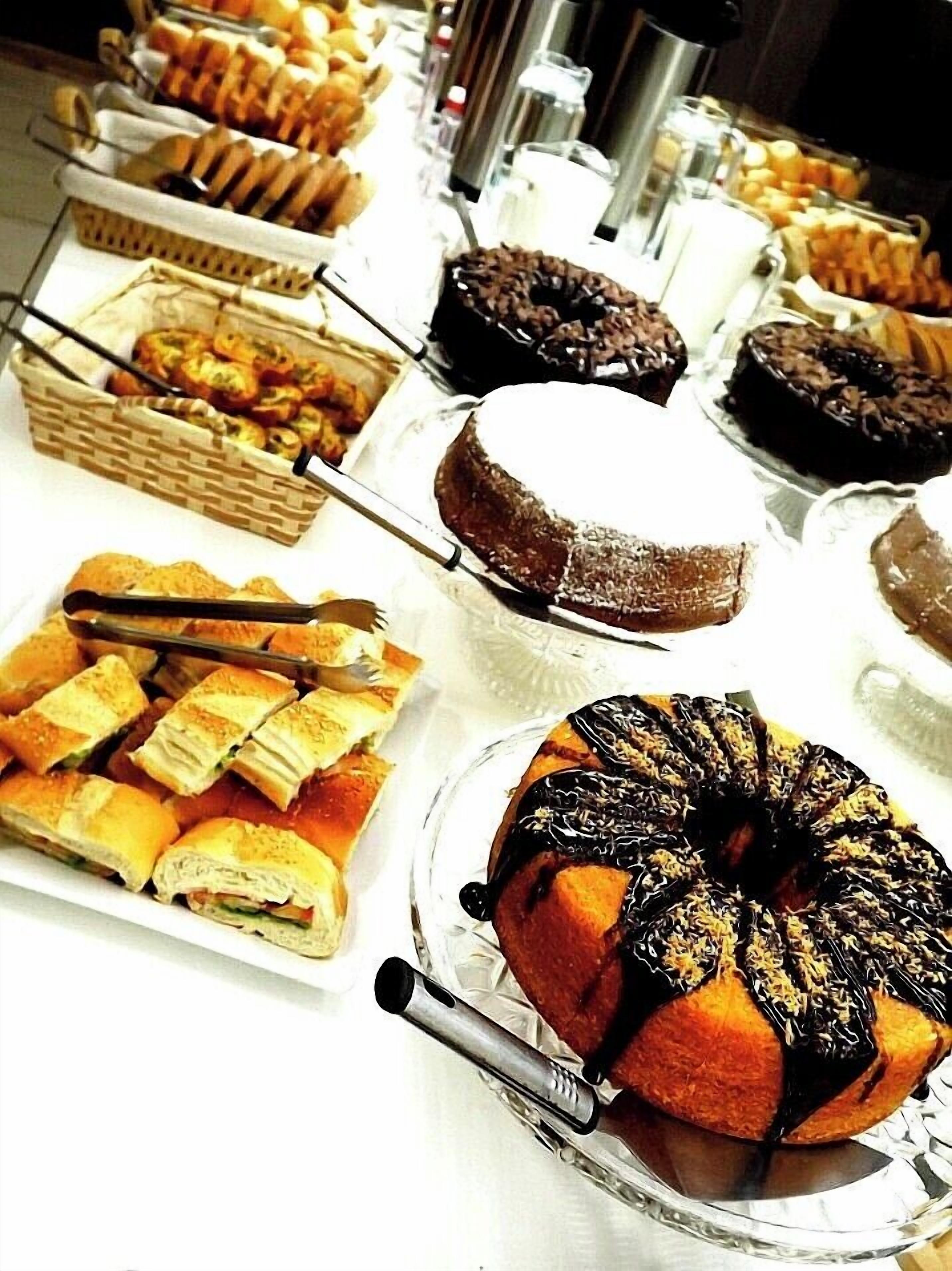 A buffet table with various baked goods including pastries, sandwiches, and a cake.