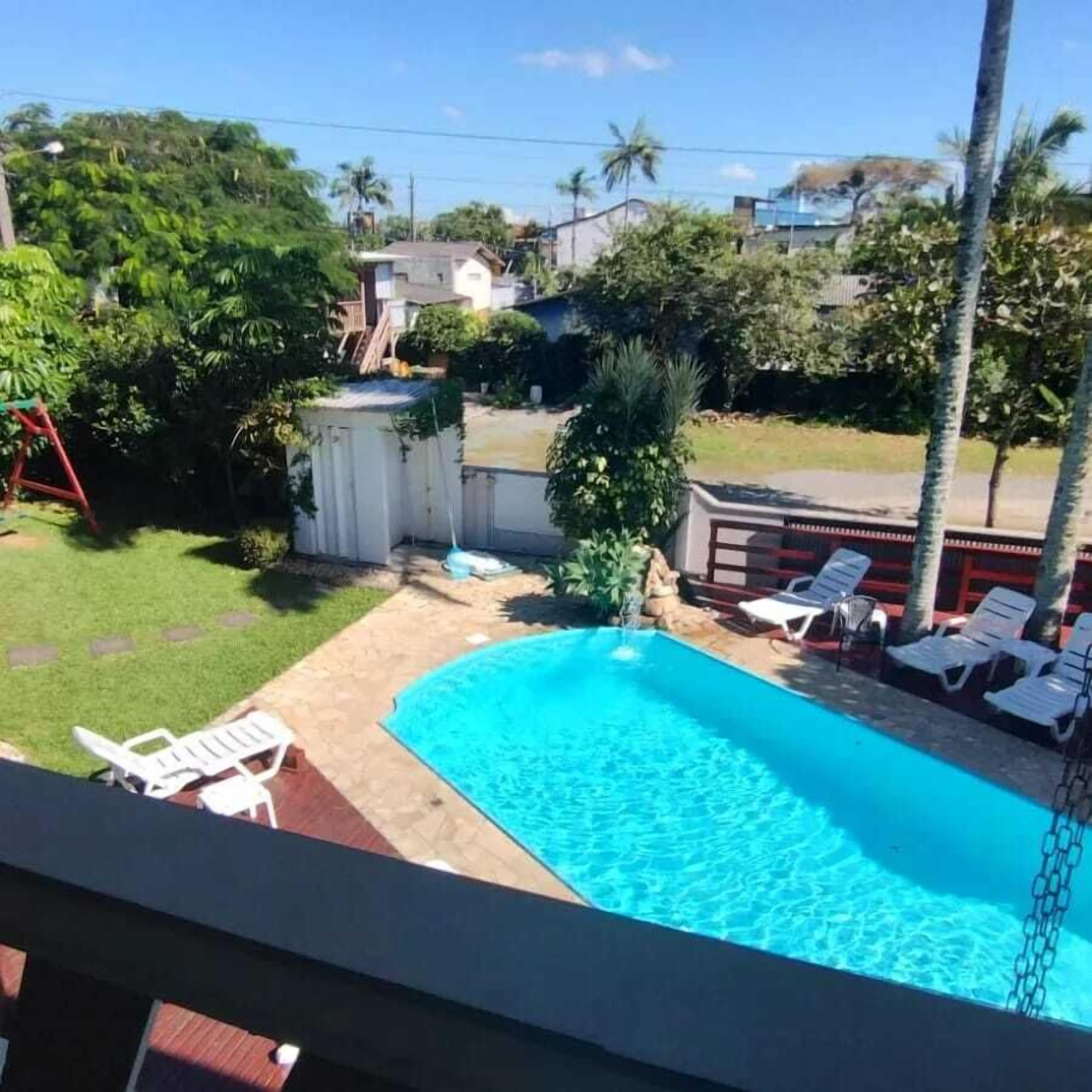 A backyard with a swimming pool, lounge chairs, and a small shed.