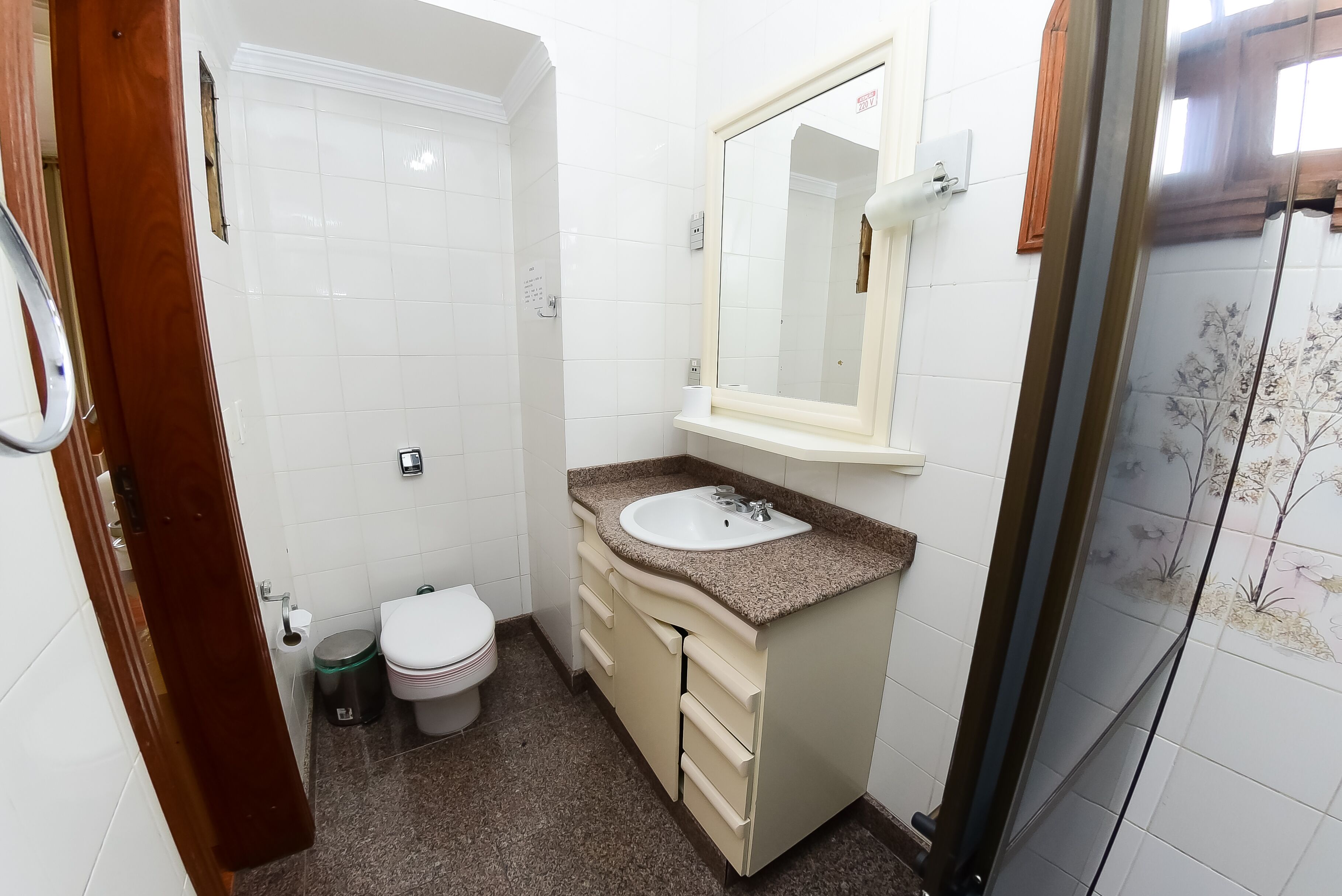 A bathroom with a toilet, sink, and shower area.