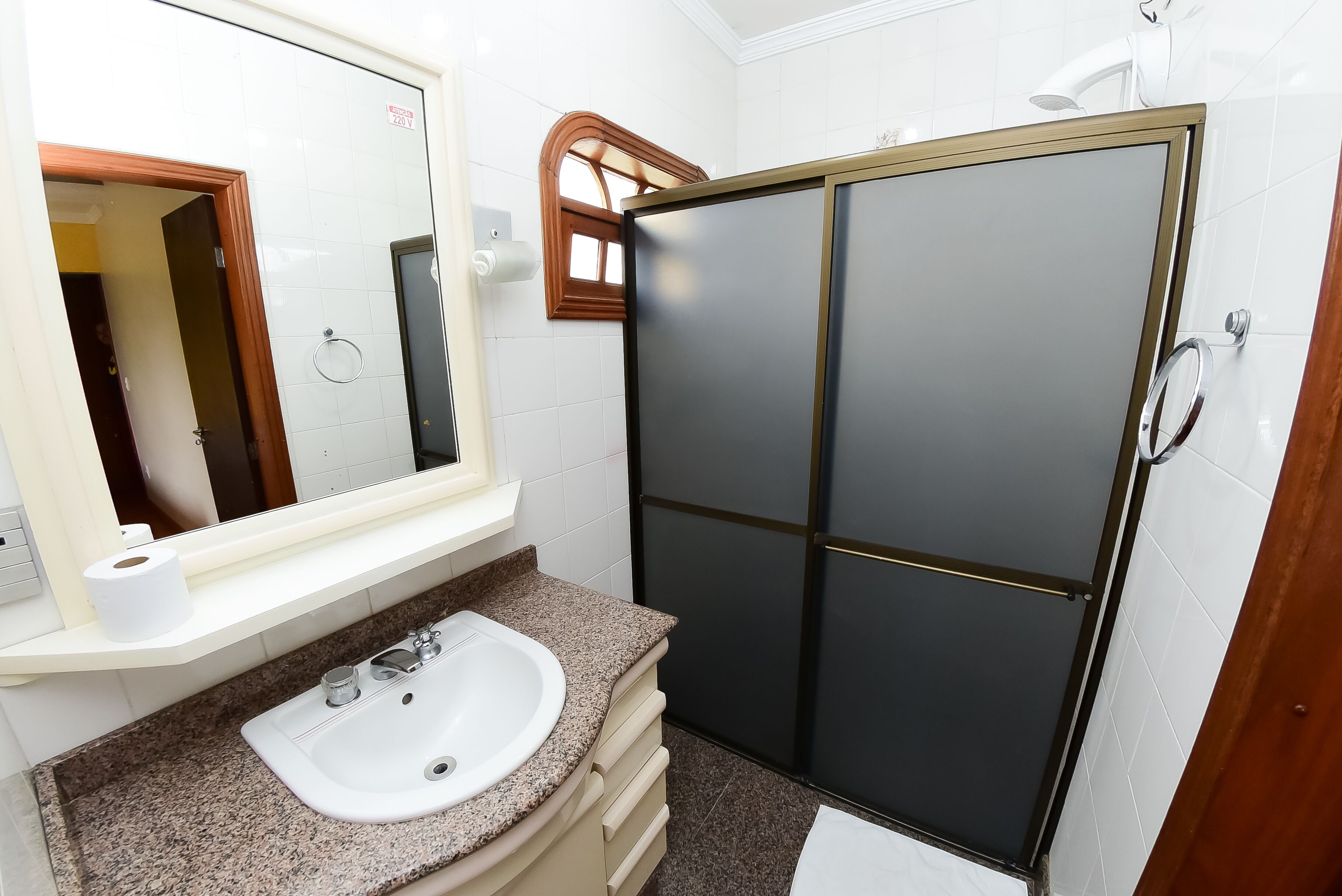 Baño con lavamanos, espejo y cabina de ducha.