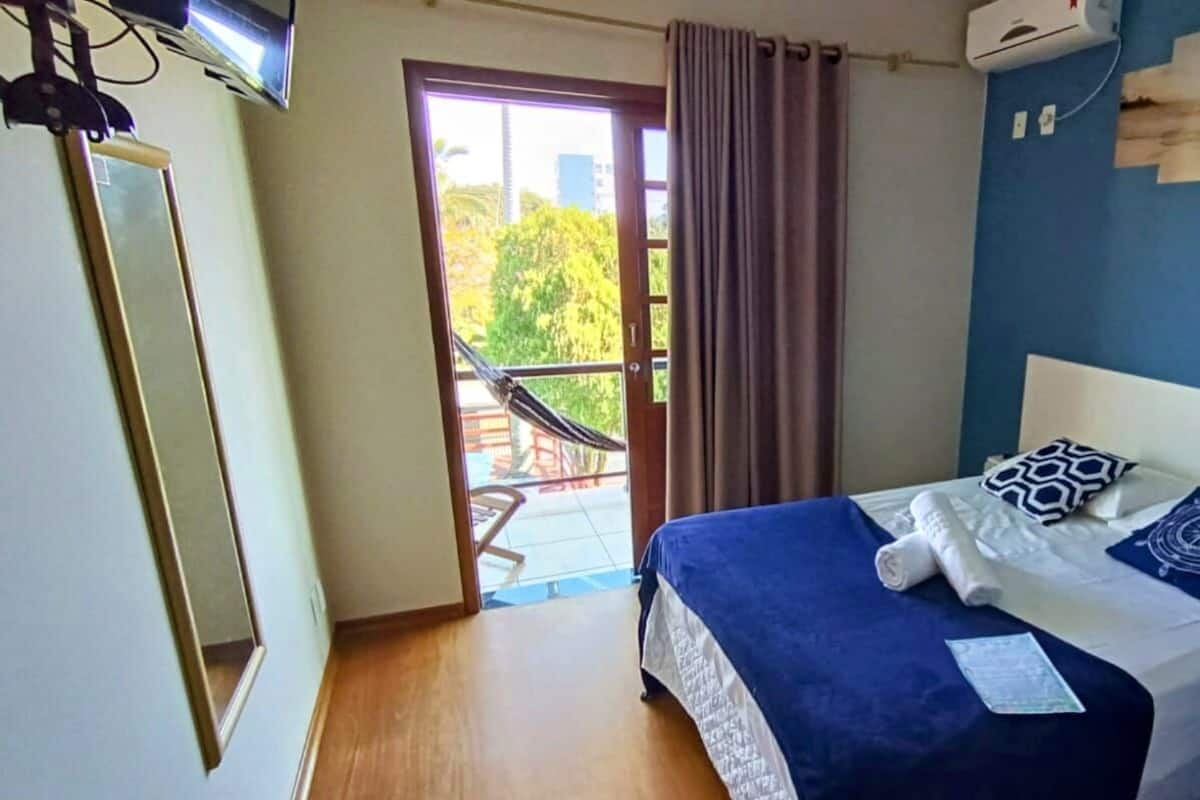 A bedroom with a bed, a window, a door, and a view of the outdoors.