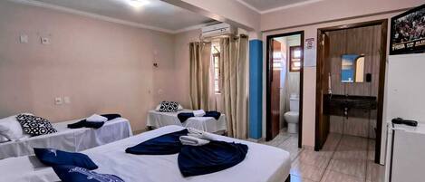 A hotel room with two beds, a small table, a sink, and a mirror.