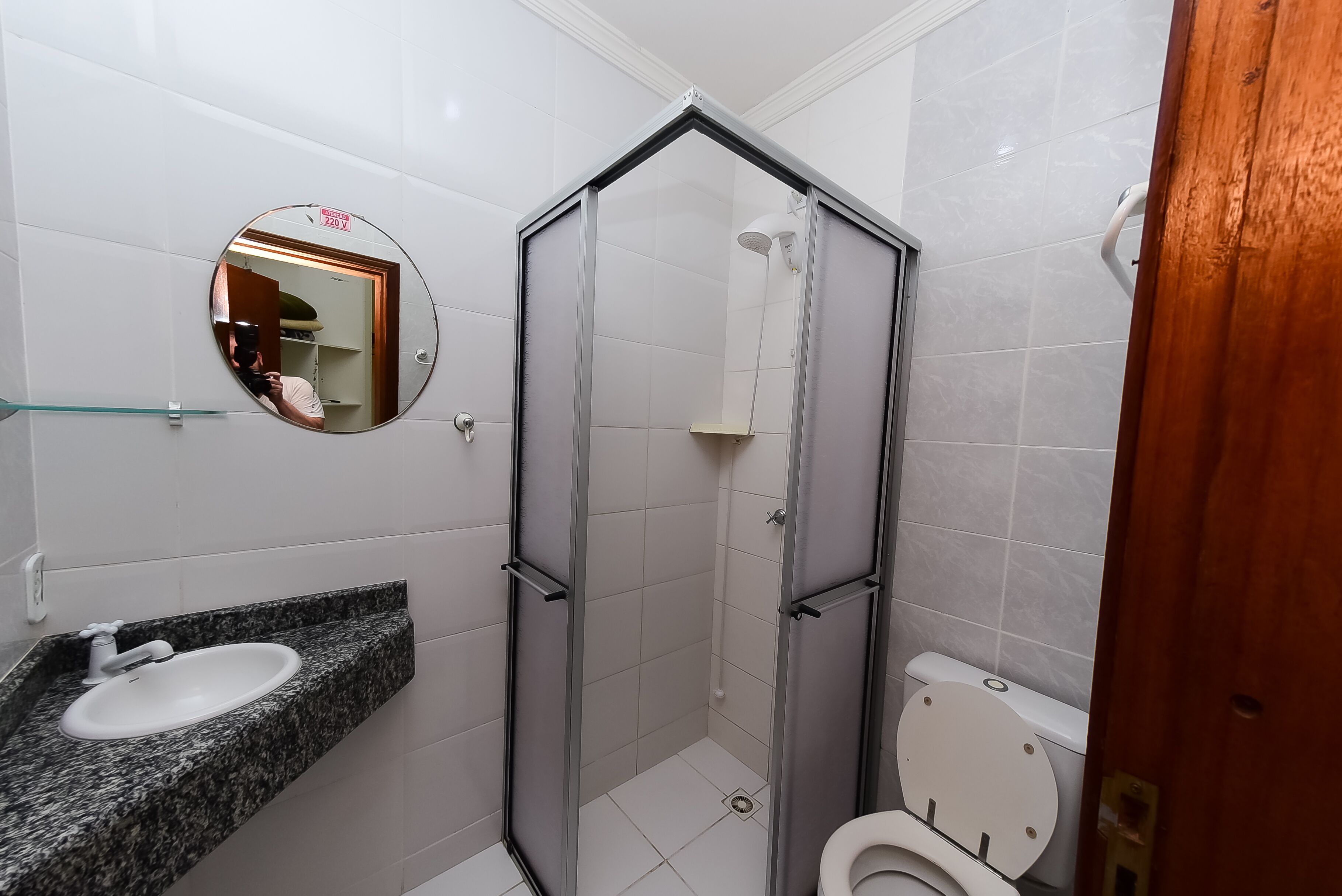 A bathroom with a glass-enclosed shower, a sink with a marble countertop, and a toilet.