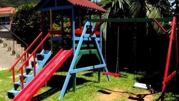 Kids can play and climb in this fun outdoor play area surrounded by lush greenery and palm trees.