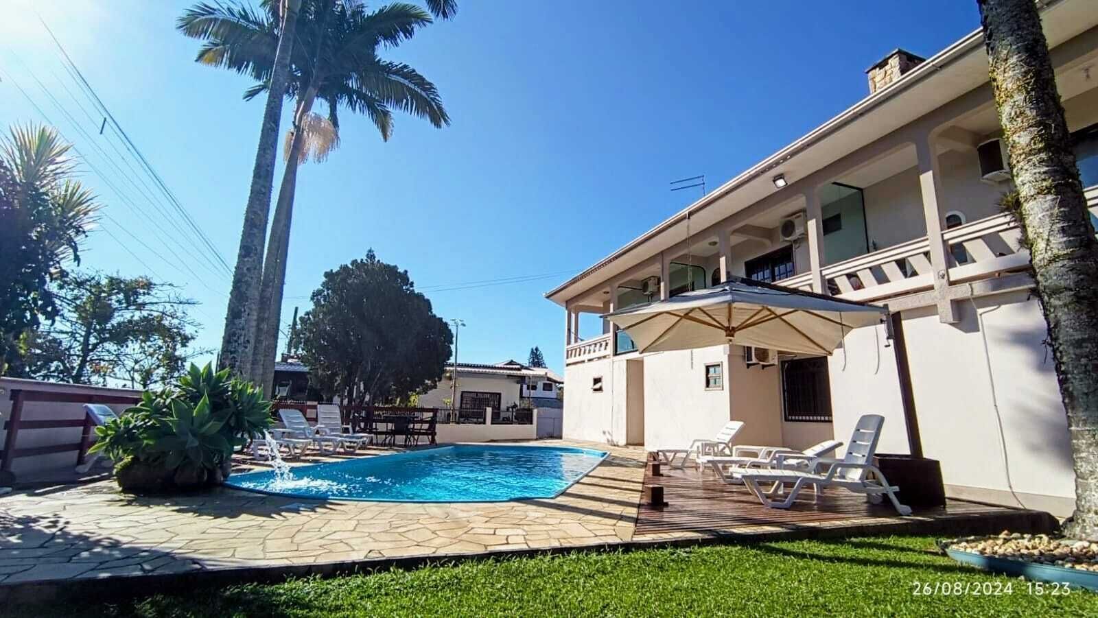 A pool area with lounge chairs and a covered seating area.