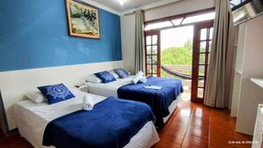 Habitación de hotel con dos camas, un cuadro en la pared y vistas a través de un ventanal.