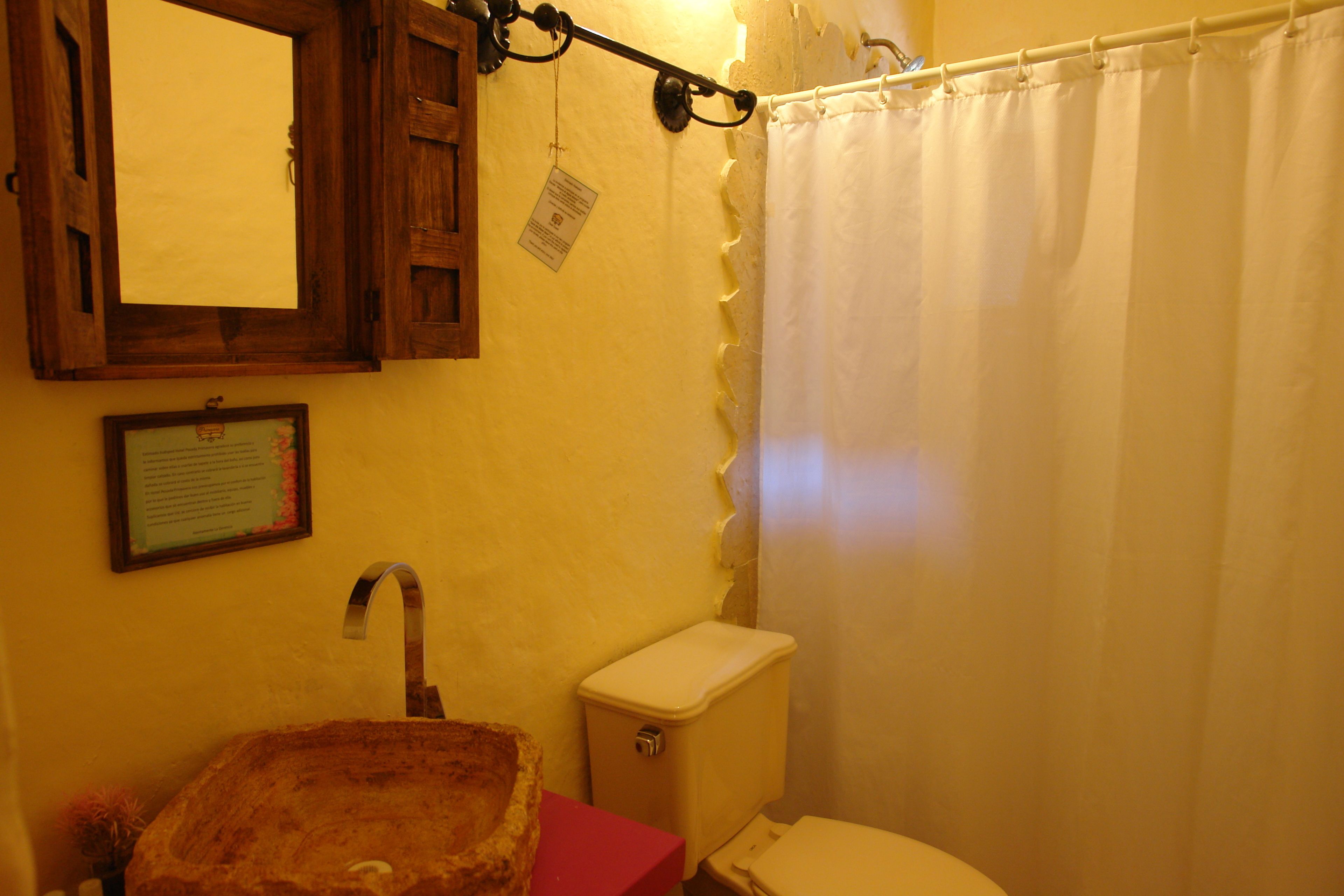 Un baño con lavamanos de madera, inodoro y cortina de ducha.
