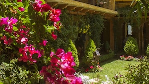 Ein zweistöckiges Gebäude mit Balkon, umgeben von einem Garten mit verschiedenen Pflanzen und Blumen.