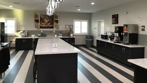 A modern kitchen with a central island, black and white striped flooring, and overhead pendant lighting. - Grand Villa Inn & Suites Chinatown (Houston)