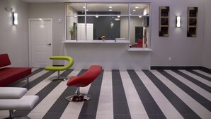 A waiting area with striped flooring, a reception desk, and modern chairs. - Grand Villa Inn & Suites Chinatown (Houston)