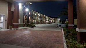 A hotel entrance with a covered walkway, palm trees, and a parking area. - Grand Villa Inn & Suites Chinatown (Houston)
