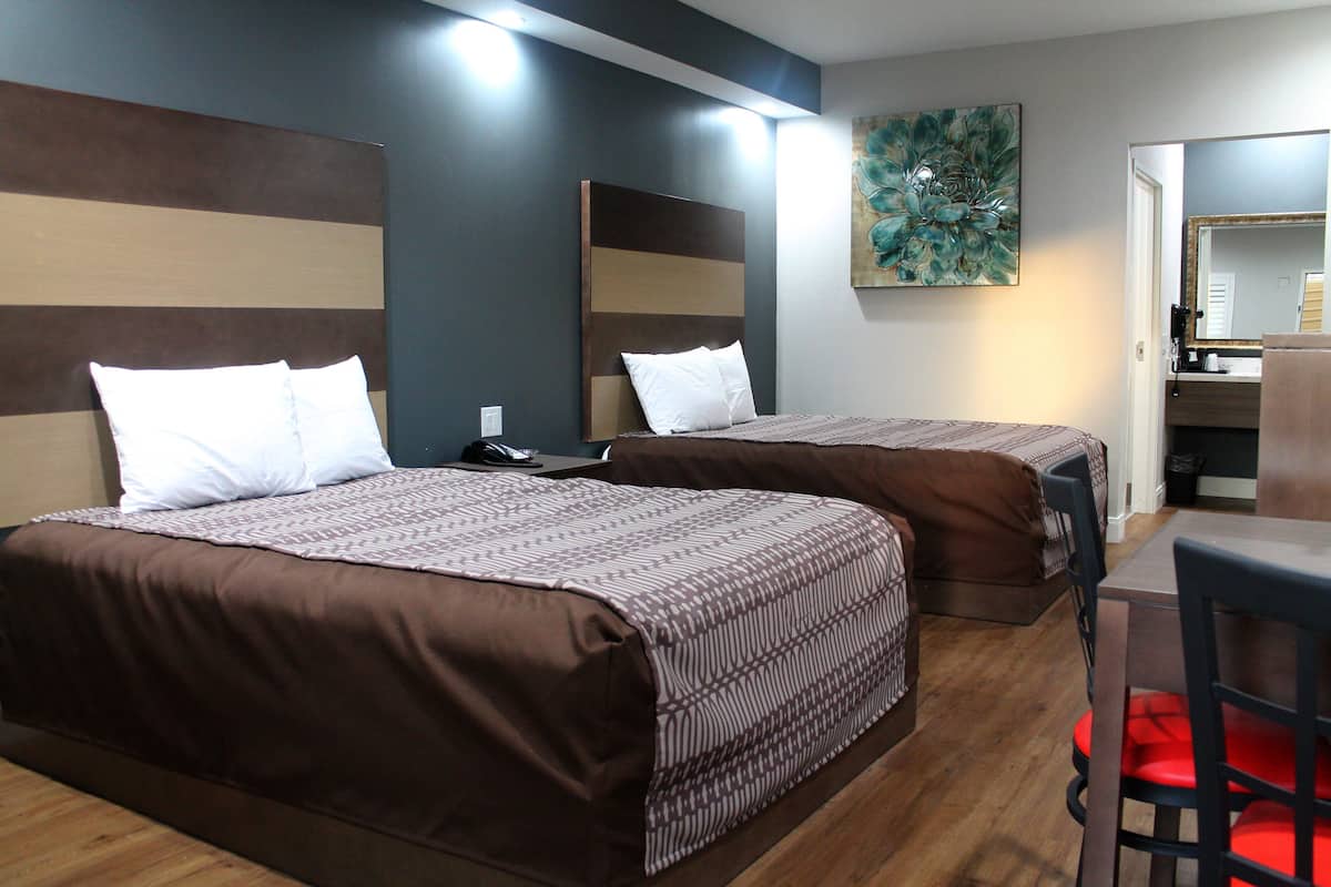 A hotel room with two beds, a desk, and a chair.