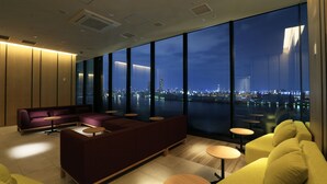 A modern hotel lobby with a large seating area, a city view through large windows, and a clean, contemporary design. - The Singulari Hotel & Skyspa at Universal Studios Japan (Osaka)