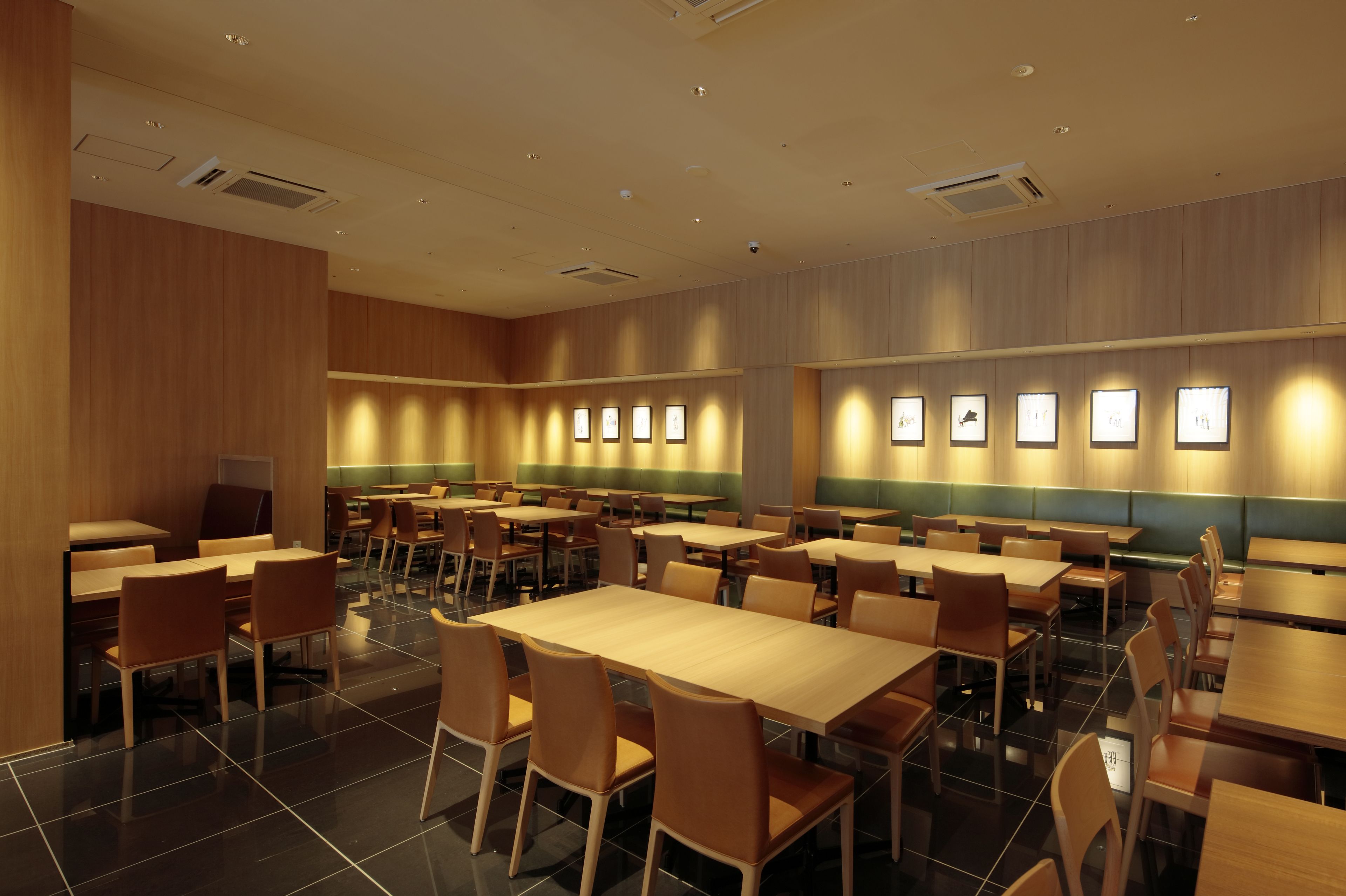 A spacious restaurant with multiple tables and chairs, wooden panel walls, and framed pictures on the walls.
