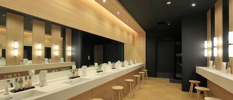 A modern bathroom with a long vanity, multiple sinks, and wooden stools.